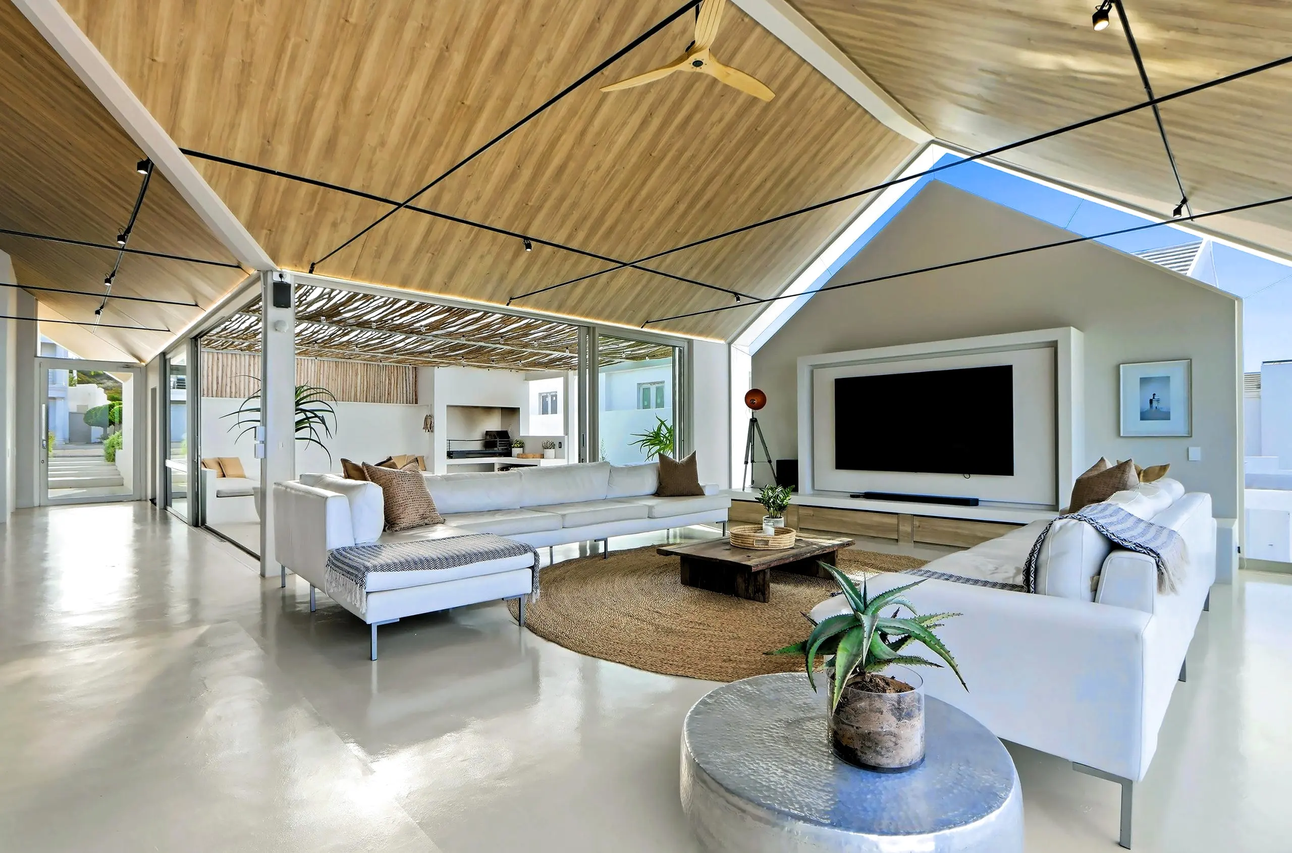 Wide view of the upper lounge with the braai courtyard visible through sliding glass